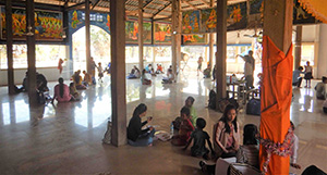 Photo of people sitting in several separate groups in a large building 