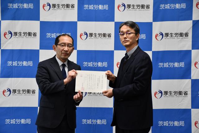 右に茨城労働局長、左に宇野理事、2人で認定通知書を真ん中に掲げている。
